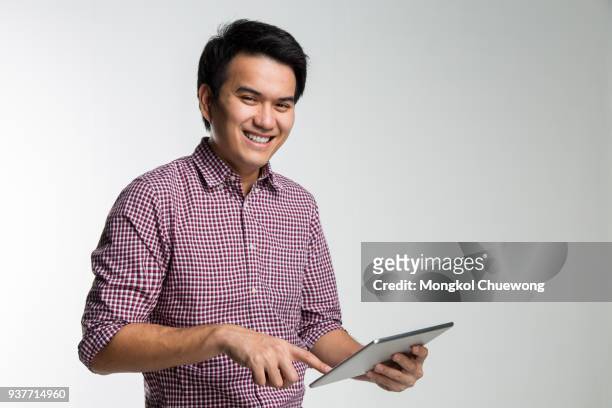 businessman with digital tablet. handsome young asian business man working on digital tablet and smiling while standing isolated on white background - man standing full body stock pictures, royalty-free photos & images