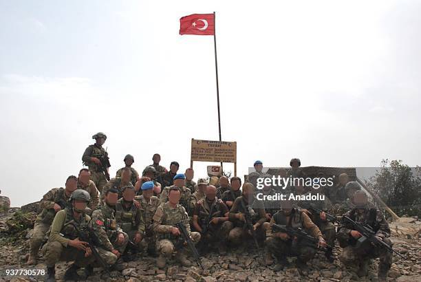 Turkish soldiers pose for a photo in front of a signboard, placed for martyred soldiers, in Bilal village of Afrin as they conduct search works for...