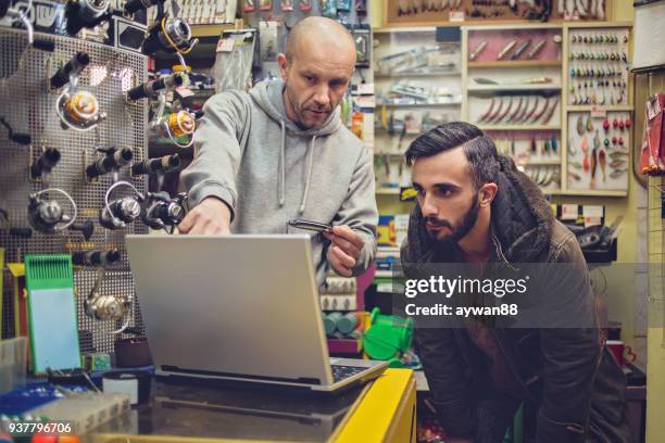 young man buying new fishing equipment - barbed hook stock pictures, royalty-free photos & images