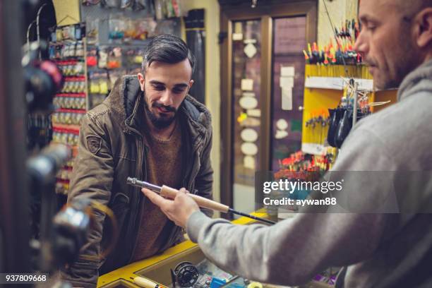 young man buying fishing rod - rod stock pictures, royalty-free photos & images