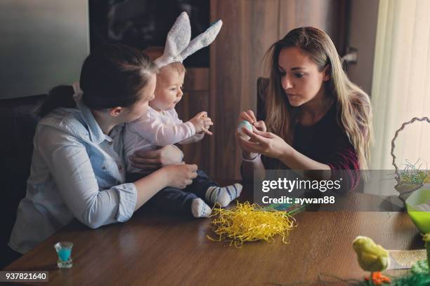 young mother and her baby having fun while painting eggs for easter - family rabbit stock pictures, royalty-free photos & images