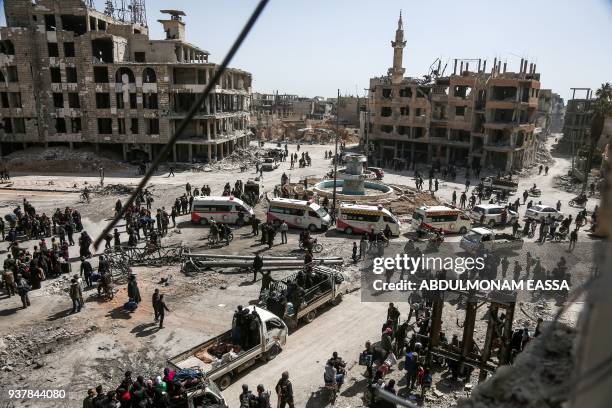 Picture taken on March 25, 2018 shows Syrian Red Crescent ambulances waiting as people prepare to evacuate from the town of Arbin in the Eastern...