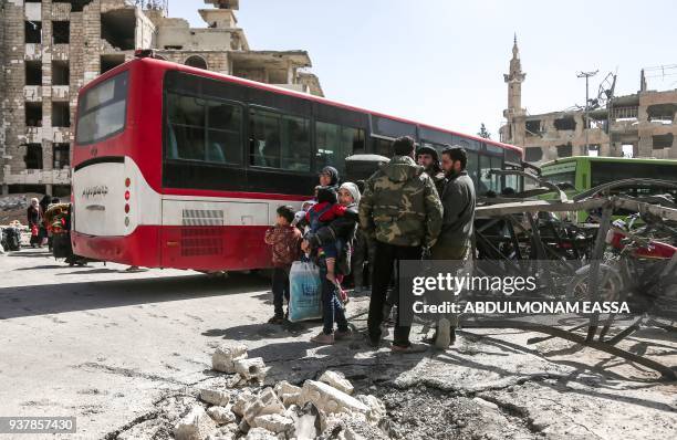 Syrian civilians and rebel fighters prepare to embark aboard a bus during the evacuation from the town of Arbin in the Eastern Ghouta region on the...