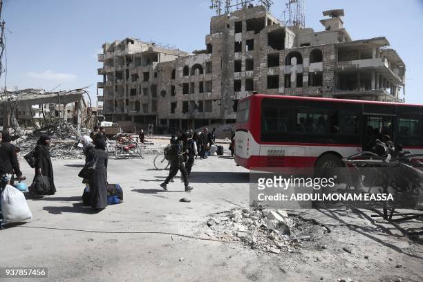 Syrian civilians prepare to embark aboard a bus during the evacuation from the town of Arbin in the Eastern Ghouta region on the outskirts of the...