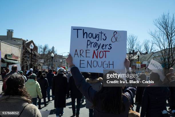 Demonstrator holds up sign "Thoughts and Prayers are Not Enough" walking down South Street during the March For Our Lives in Morristown, New Jersey,...