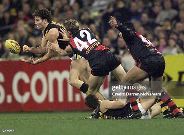 Ben Holland for Richmond handballs to a team mate dispite being tackled by Danny Jacobs for Essendon, during the AFL round 22 game between the...