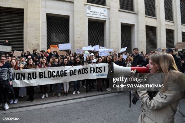 Student speaks in a megaphone next to demonstrators holding placards and a banner reading "No to the blocking ouf our faculties" during a rally in...