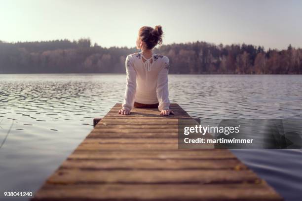 junge frauen an einem hölzernen pier an einem see in österreich - frau frühling herbst stock-fotos und bilder