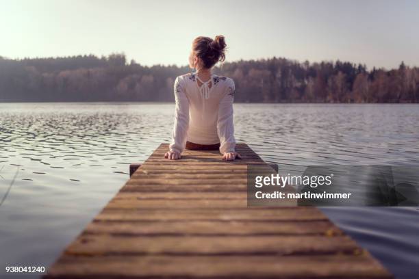 奧地利一個湖邊的木碼頭上的年輕婦女 - lakeshore 個照片及圖片檔
