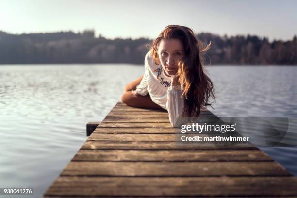 jonge vrouwen op een houten pier op een meer in oostenrijk - martinwimmer stockfoto's en -beelden