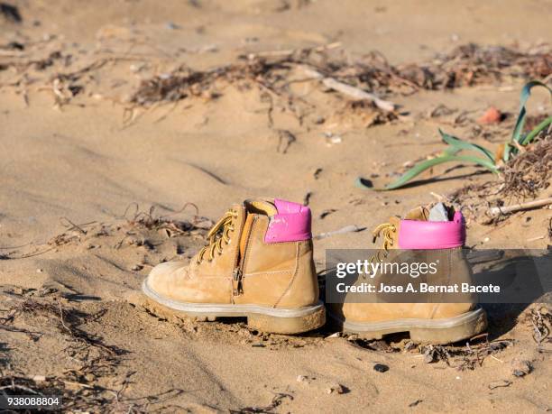 a couple of leather boots  and socks of pink color, abandoned over on  sand on the beach. - lost sock stock pictures, royalty-free photos & images