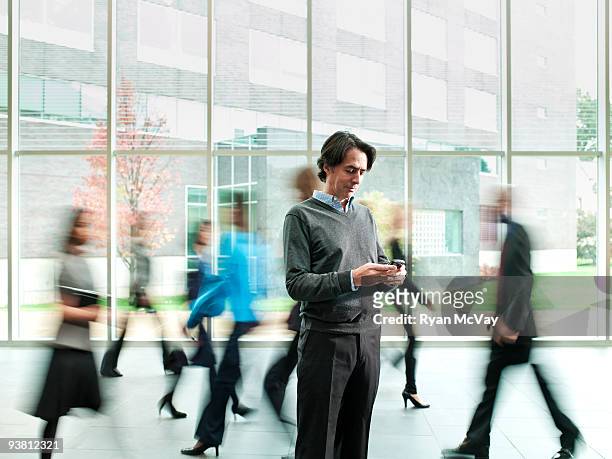 business man checking phone, crowd moving past - bewegungsunschärfe stock-fotos und bilder