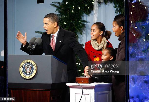 President Barack Obama presses the button to light up the National Christmas Tree with daughters Malia and Sasha, and first lady Michelle during the...