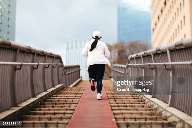 overweight woman running at stairs - fat asian woman stock pictures, royalty-free photos & images