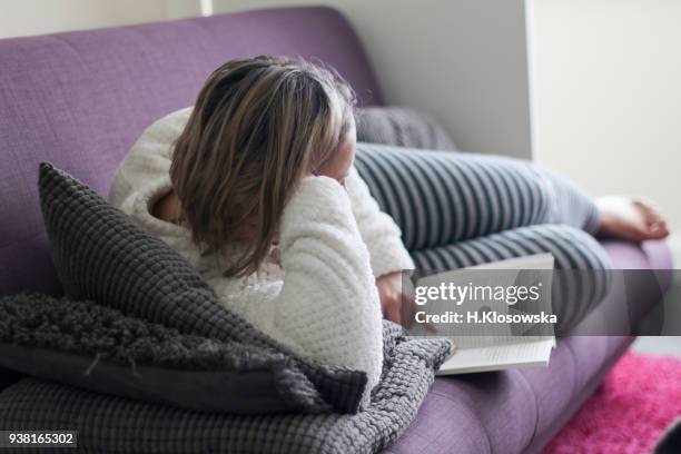 woman reading on the sofa - hourglass books fotografías e imágenes de stock