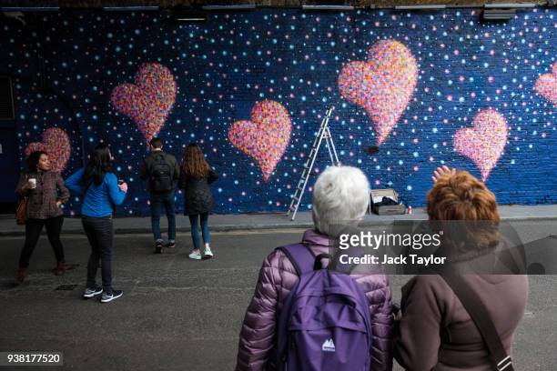 Members of the public look at a mural by British-born Australian artist James Cochran, known as 'Jimmy C', to commemorate the victims of the London...