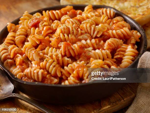 rotini pasta in roasted tomato and garlic sauce with garlic bread - pasta with bolognese sauce stock pictures, royalty-free photos & images
