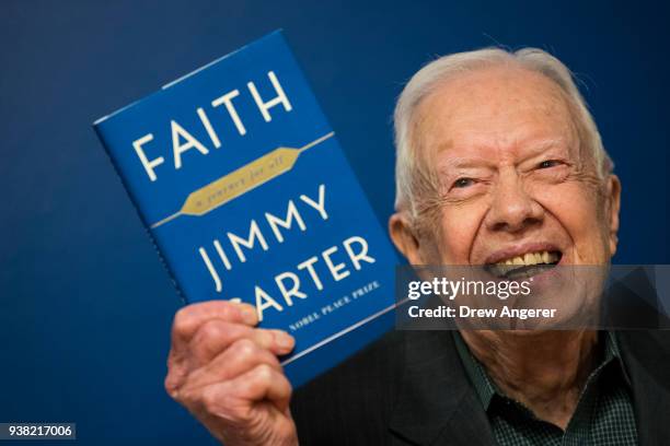 Former U.S. President Jimmy Carter holds up a copy of his new book 'Faith: A Journey For All' at a book signing event at Barnes & Noble bookstore in...
