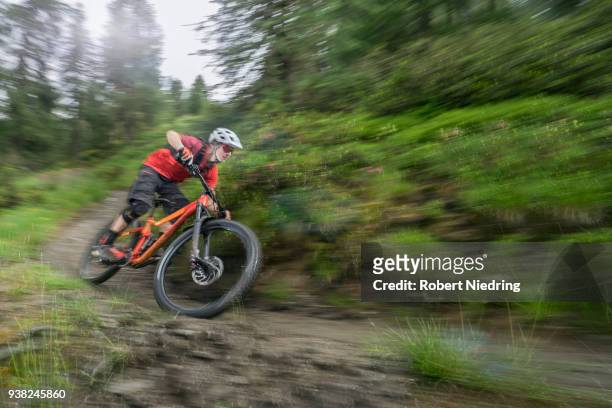 mountain biker speeding on track through forest path, trentino-alto adige, italy - ganzkörperansicht photos et images de collection