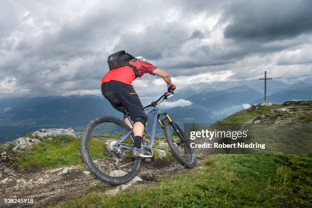 rear view of mountain biker riding on uphill, trentino-alto adige, italy - ein mann allein fotografías e imágenes de stock