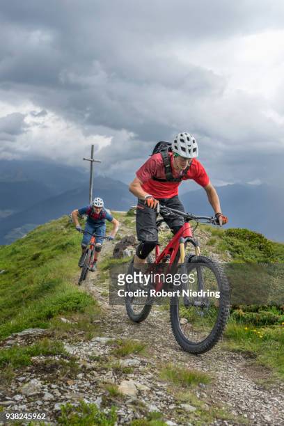 mountain bikers riding on uphill in alpine landscape, trentino-alto adige, italy - freundschaft fotografías e imágenes de stock