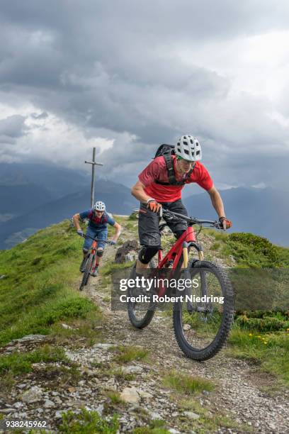 mountain bikers riding on uphill in alpine landscape, trentino-alto adige, italy - schutzbrille foto e immagini stock