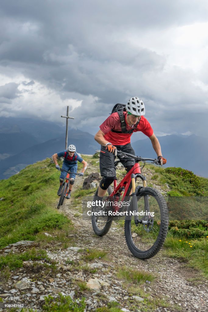 Mountain bikers riding on uphill in alpine landscape, Trentino-Alto Adige, Italy