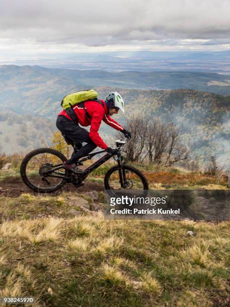 man riding electric mountain bike on single trail, vosges, france - radfahren stockfoto's en -beelden