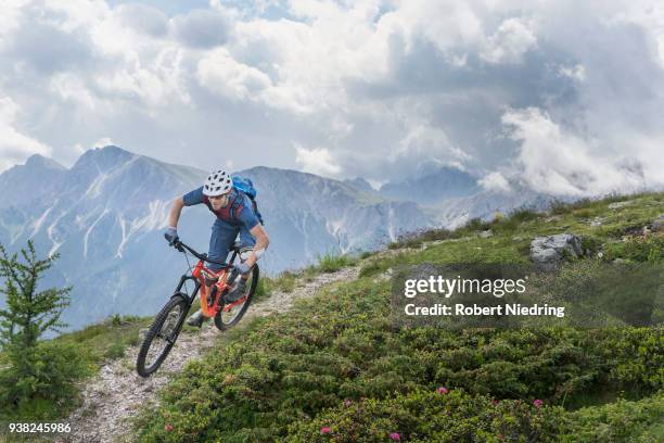 mountain biker riding on uphill in alpine landscape, trentino-alto adige, italy - radfahren stockfoto's en -beelden