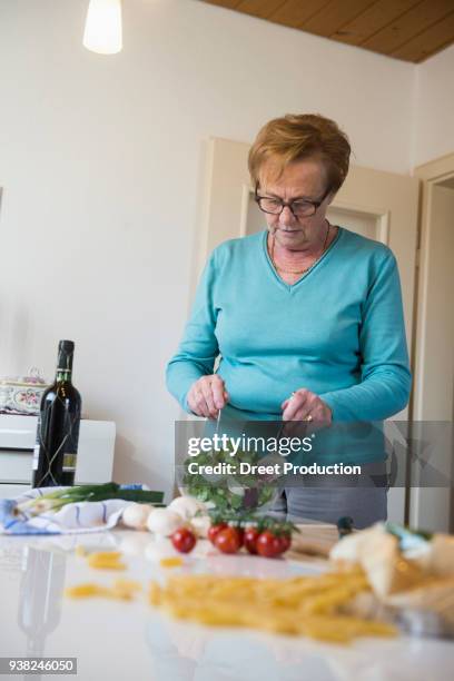 old woman mixing salad on the kitchen table - alterungsprozess 個照片及圖片檔