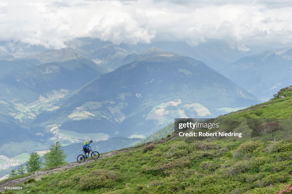 Mountain biker riding on uphill in alpine landscape, Trentino-Alto Adige, Italy