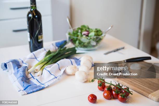tomatoes, mushrooms, salad, spring onions and a bottle of red wine on kitchen table - organisch fotografías e imágenes de stock