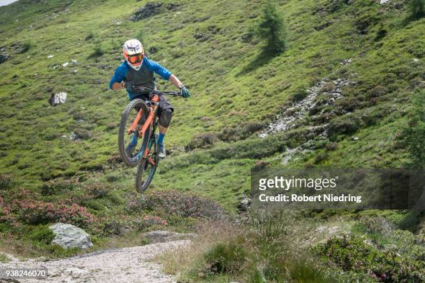 mountain biker jumping with speed on forest path, trentino-alto adige, italy - ganzkörperansicht photos et images de collection