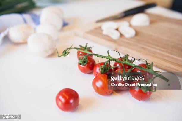 tomatoes, mushrooms and cutting board on kitchen table - essen am tisch stock pictures, royalty-free photos & images