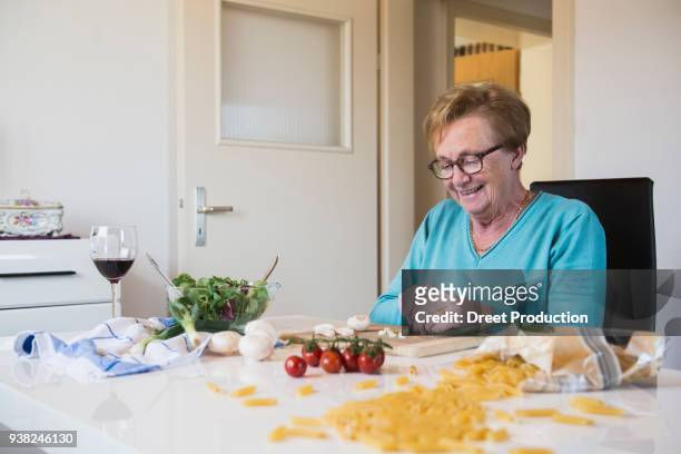 old woman cutting spring onions at the kitchen table - frau in küche bildbanksfoton och bilder