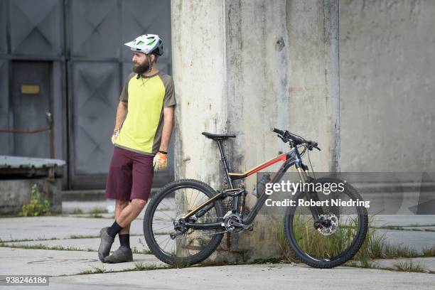 mountain biker stands close to his bike in city - fahrrad fahren stockfoto's en -beelden