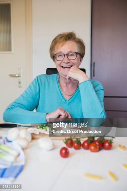 old woman at the kitchen table preparing food - tisch essen stockfoto's en -beelden