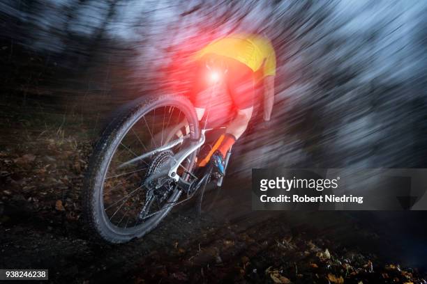 mountain biker speeding at night on forest track, bavaria, germany - sorglos fotografías e imágenes de stock