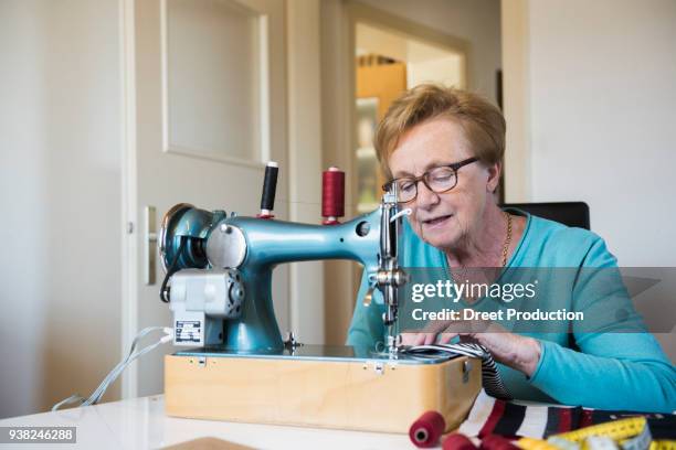 old woman working at sewing machine - faden fotografías e imágenes de stock