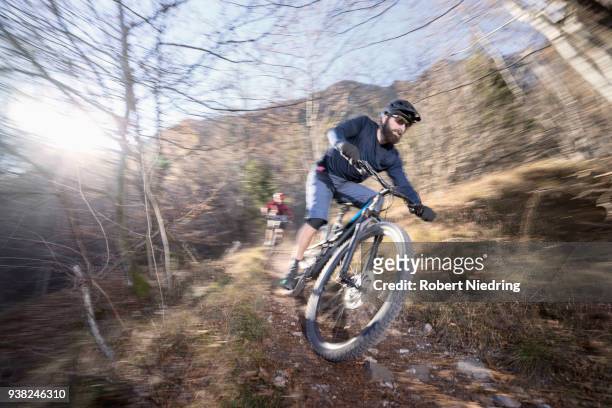 mountain bikers riding downhill in alpine landscape, trentino, italy - ganzkörperansicht photos et images de collection