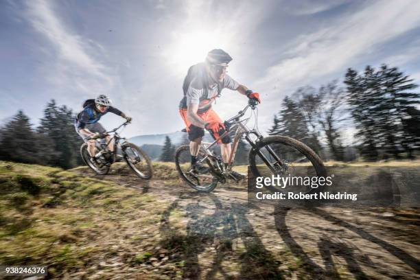 mountain bikers speeding on dirt path, bavaria, germany - schutzbrille foto e immagini stock