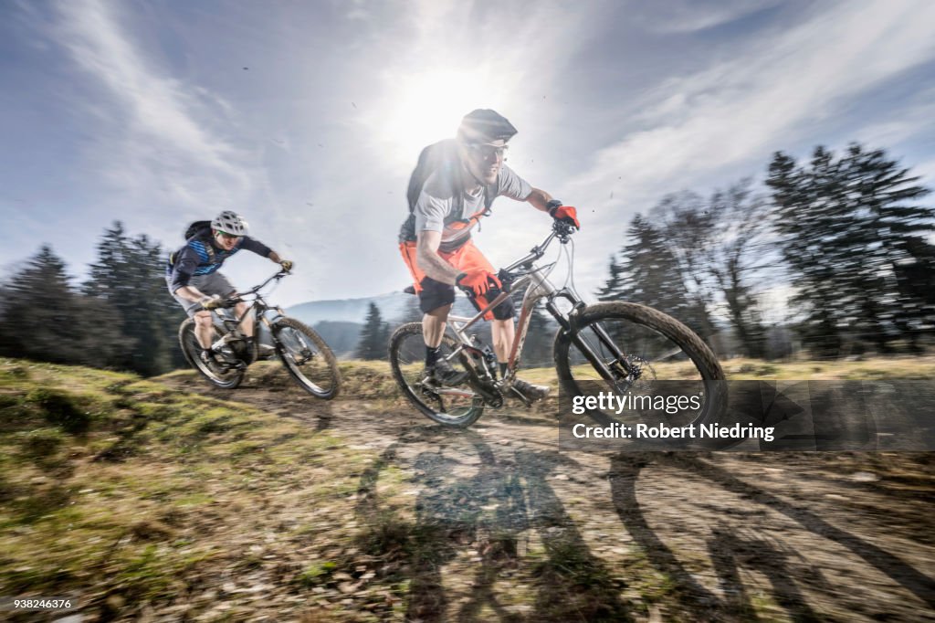 Mountain bikers speeding on dirt path, Bavaria, Germany