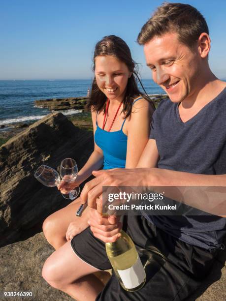 young couple on the beach drinking white wine, beach of azkorri, getxo, biscay, spain - lächeln stock pictures, royalty-free photos & images