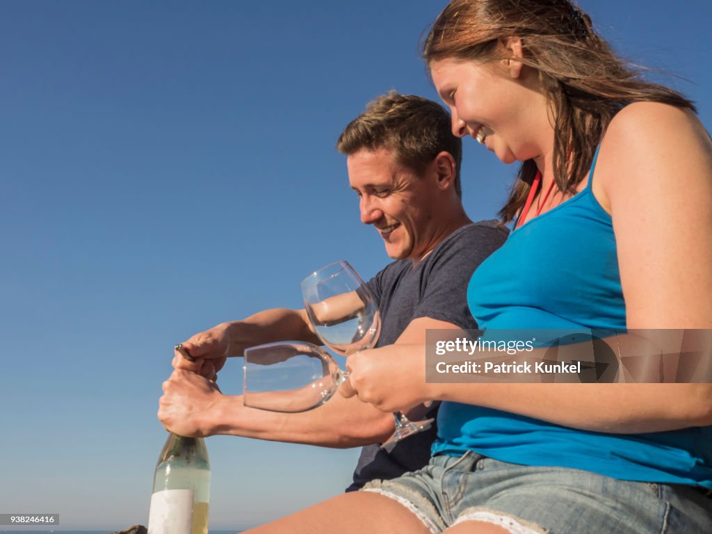 Young couple drinking white wine, Beach of Azkorri, Getxo, Biscay, Spain