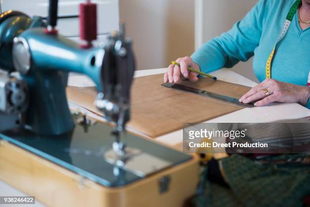 old woman measuring with a ruler on sewing desk - menschliches körperteil foto e immagini stock