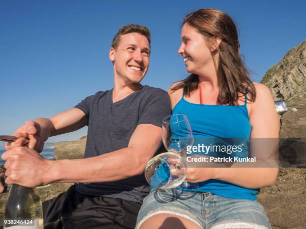young couple drinking white wine, beach of azkorri, getxo, biscay, spain - sorglos foto e immagini stock
