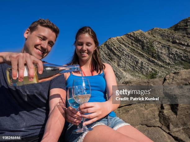 young couple drinking white wine, beach of azkorri, getxo, biscay, spain - junger erwachsener stock pictures, royalty-free photos & images