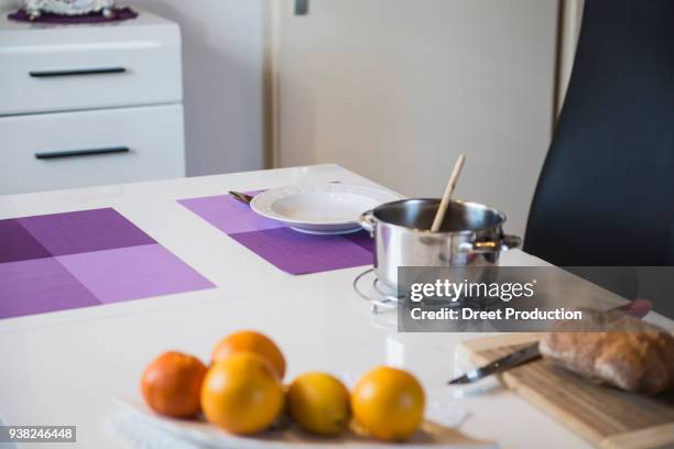 breakfast table with a pot, bread, soup plate and orange fruit - essen tisch stock pictures, royalty-free photos & images