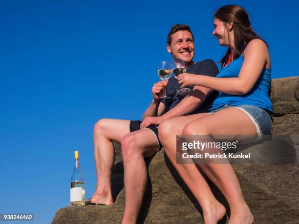 young couple drinking white wine, beach of azkorri, getxo, biscay, spain - sorglos fotografías e imágenes de stock