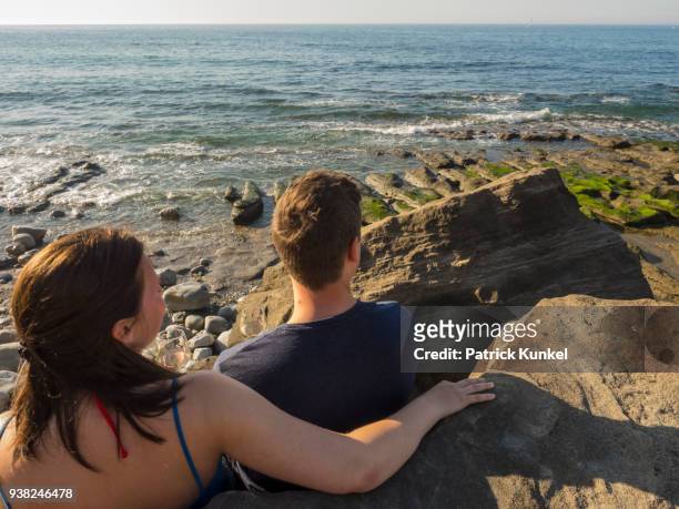 young couple on the beach drinking white wine, beach of azkorri, getxo, biscay, spain - sorglos fotografías e imágenes de stock